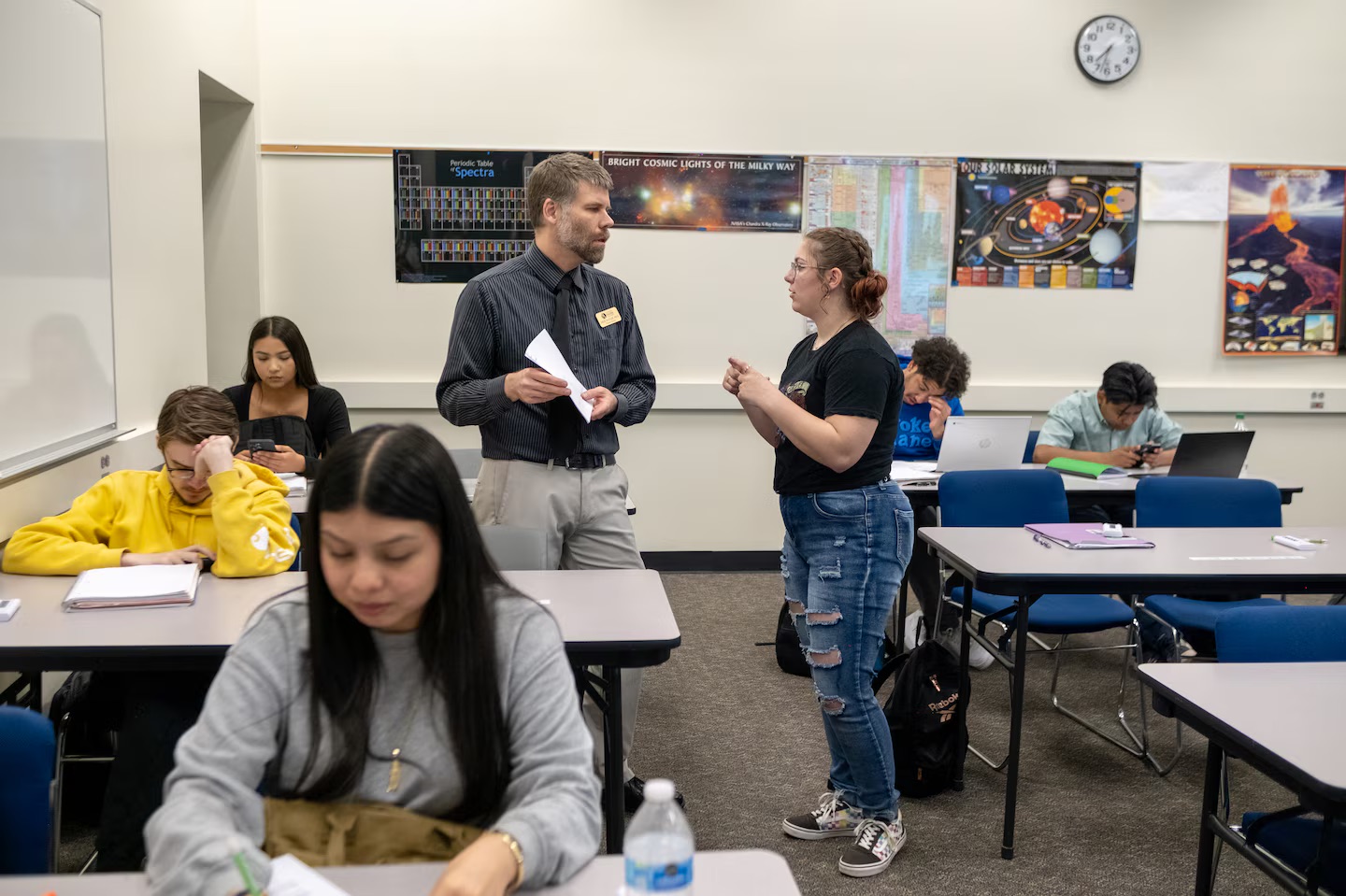 A student talks to a professor inside of a classroom.