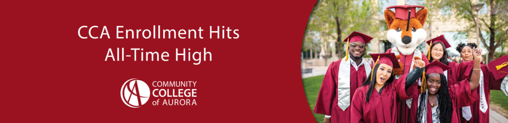 Group of smiling graduates in maroon caps and gowns celebrating with CCA’s fox mascot. Text below reads: 'CCA Enrollment Hits All-Time High.' Community College of Aurora logo at the bottom.